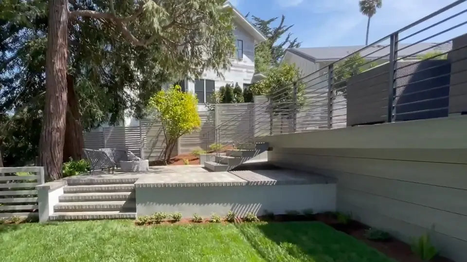 Backyard with new lawn, concrete steps and a raised paver patio