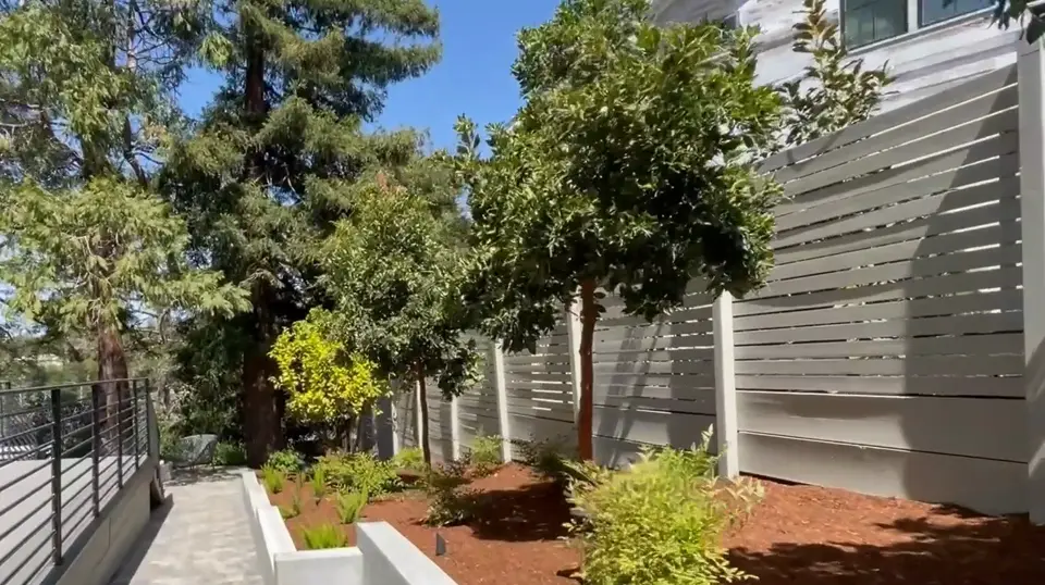 Smooth concrete retaining walls forming raised planters along a side yard